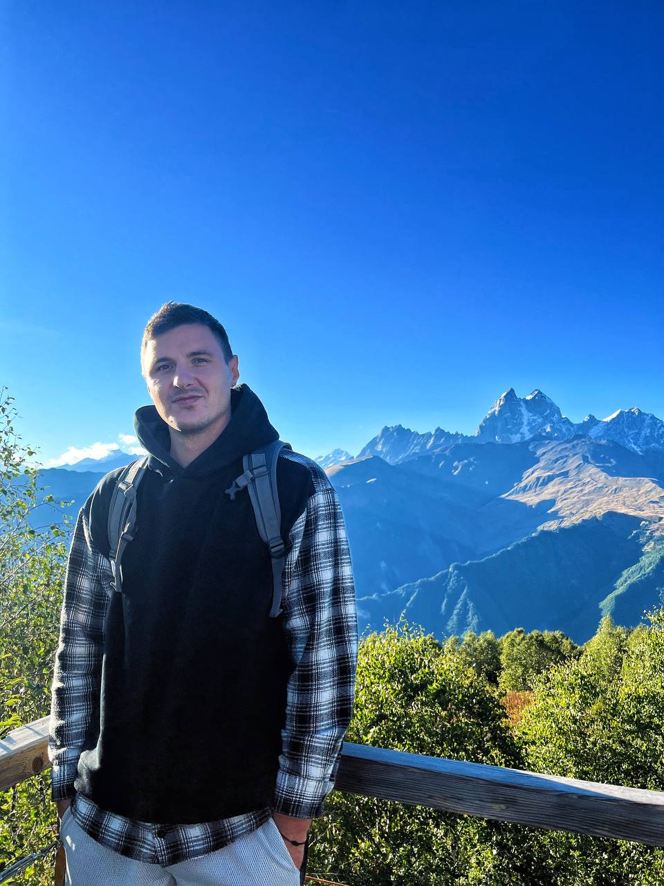 Boris Gresky smiling in a red plaid shirt and tortoise shell glasses